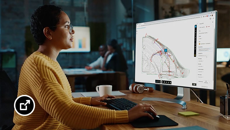 Woman sitting at a desk viewing her computer screen while using BIM Collaborate Pro software.