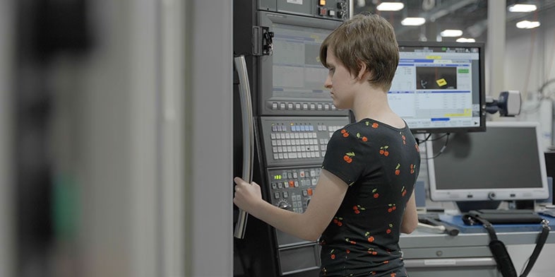 Man holding up a part in front of a screen that shows the design of the same part