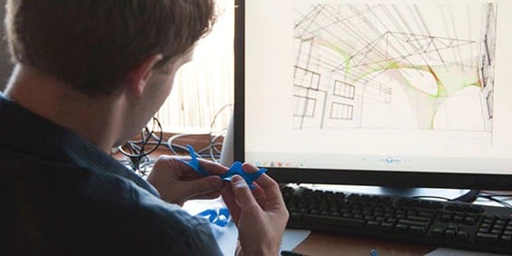 architect in front of computer with architectural model drawings