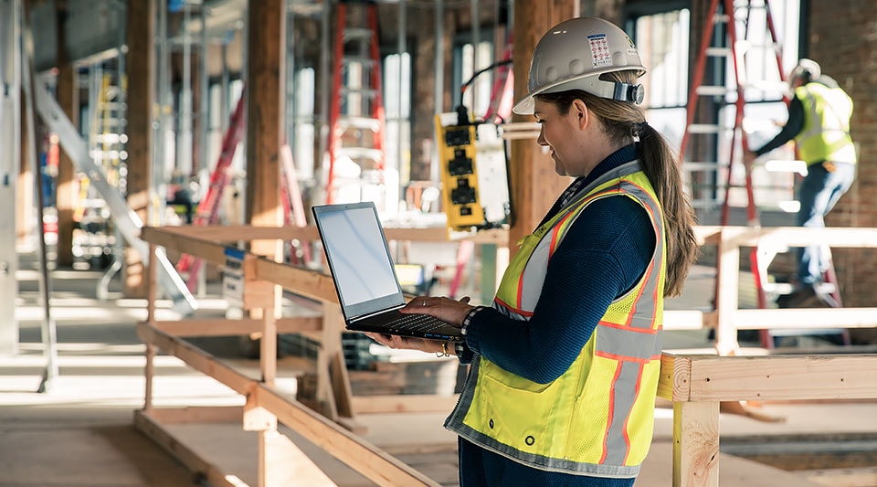 BIM professional from Fortis Construction on a construction site looking at laptop 
