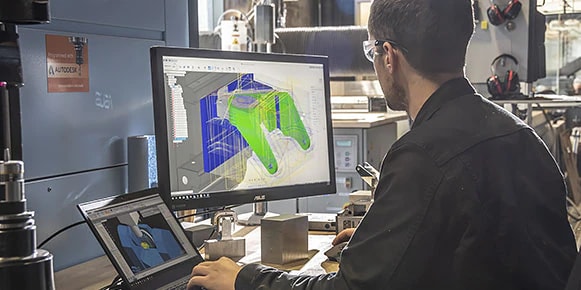 Man in workshop viewing multicolored CAD rendering on computer screen   