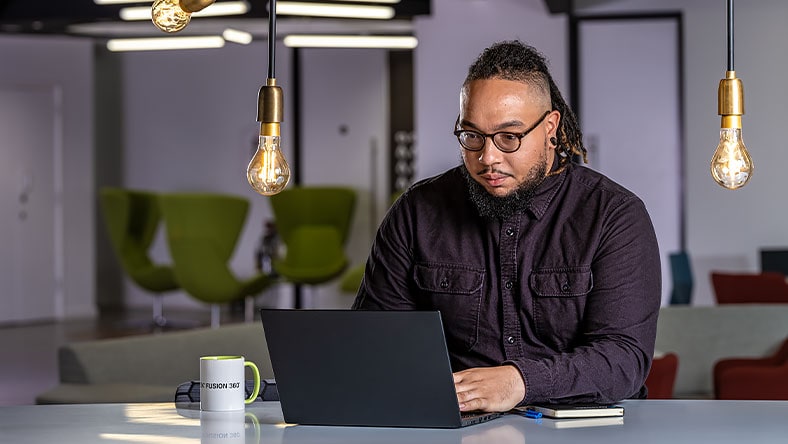 Man working on laptop sits at desk in office space