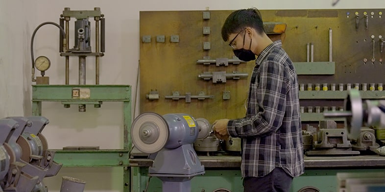 Man holding up a part in front of a screen that shows the design of the same part