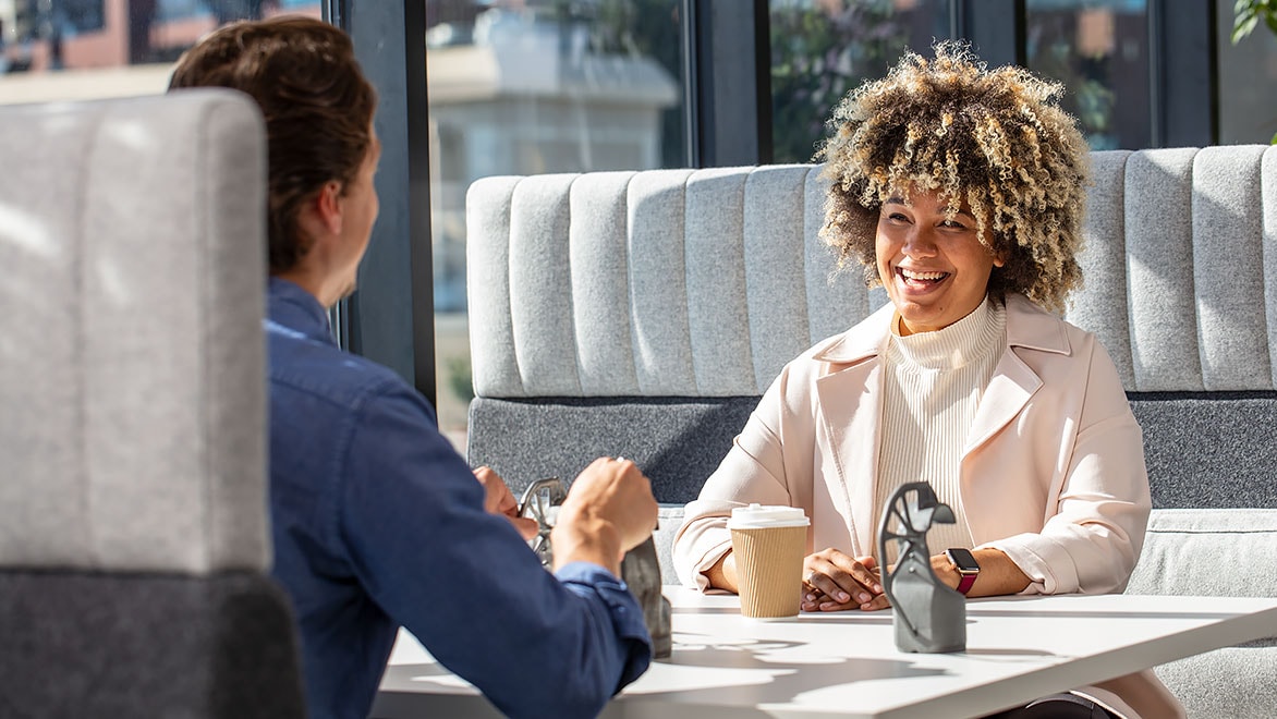 Woman in  coffee shop booth smiles at man sitting across from her