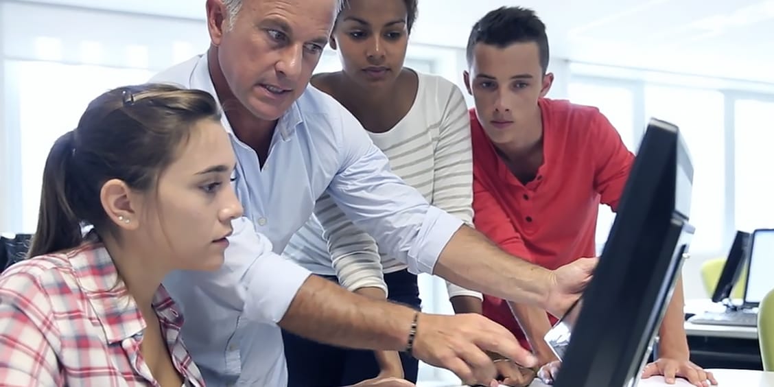 Educator and students looking at computer monitor