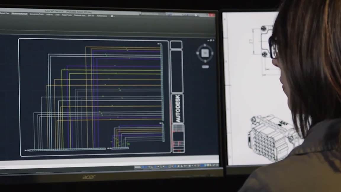 A woman working with AutoCAD software on two monitor screens 