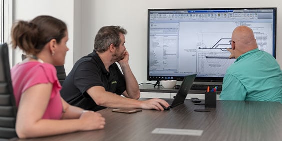 2 men and 1 woman in a conference room, looking at a design on a large screen